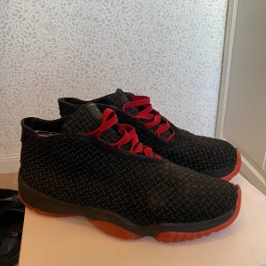 Jordans  - Säljer ett par snygga svarta sneakers med röda snören och sulor. Skorna har ett diskret mönster och ser riktigt coola ut. Perfekta för både vardag och fest! De är i bra skick och redo för nya äventyr. Det är även reflexer över hela skon. 