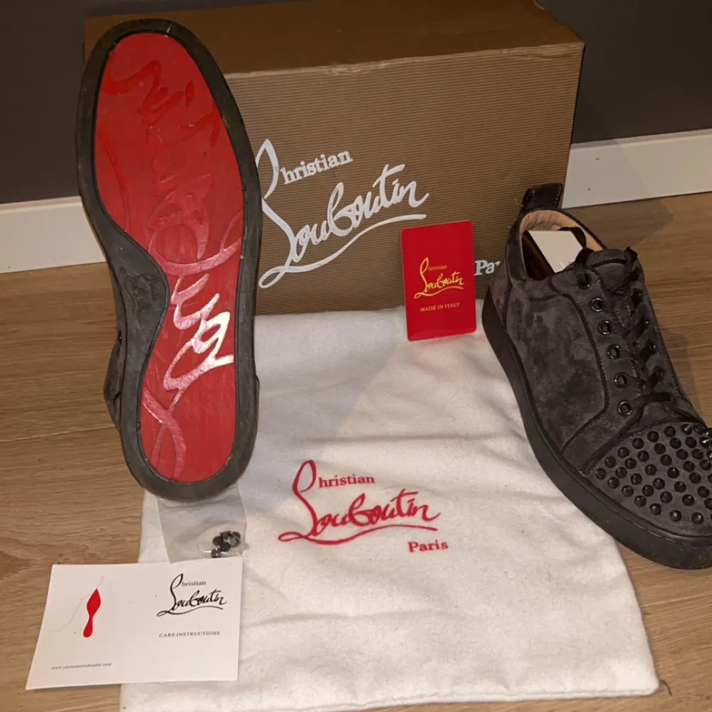 Säljer ett par gråa sneakers från Christian Louboutin i mocka med coola nitar på tån. Skorna har den ikoniska röda sulan och kommer med originalkartong och dustbag. Perfekta för att ge din outfit en edgy touch!. Skor.