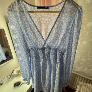 Blå blommig klänning från lager 157 - Säljer en söt och somrig blå klänning från lager 157 i storlek XS. Den har ett blommigt mönster och är gjord i ett lätt och luftigt material. Klänningen har en v-ringad design och långa ärmar, perfekt för vår och sommar. ☀️