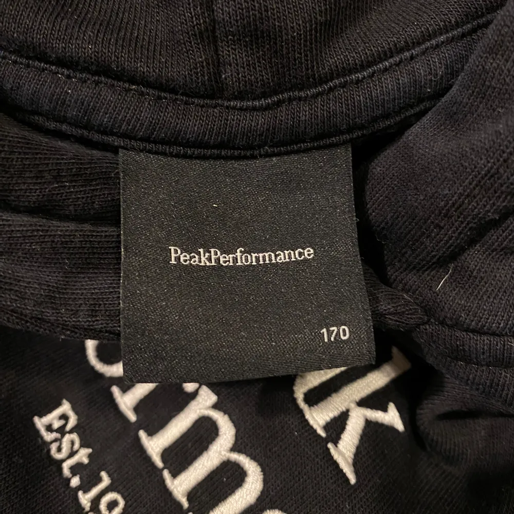 Säljer en svart hoodie från Peak Performance i mycket bra skick. Den har en klassisk design med vit logga på bröstet och en stor ficka framtill. Perfekt för höst och vinter, och den är supermjuk och bekväm. Passar både till vardags och chillkvällar. 🖤. Tröjor & Koftor.