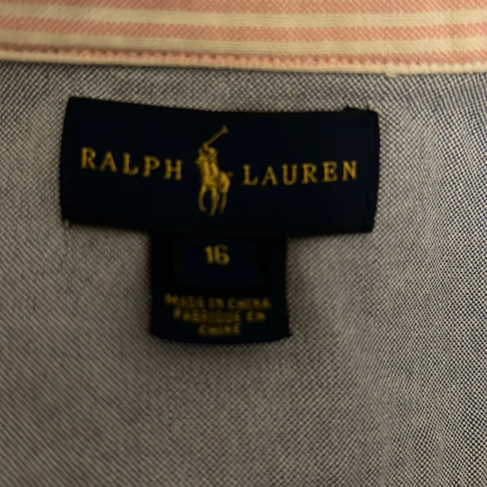 Säljer en klassisk blå skjorta från Ralph Lauren i storlek 16. Skjortan har en stilren design med knappar och det ikoniska broderade logotypen på bröstet. Perfekt för både vardag och fest! 💙. Skjortor.