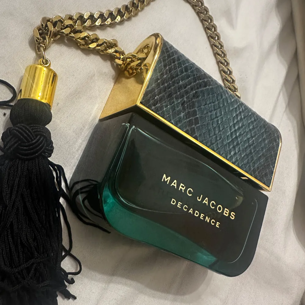 Säljer en lyxig Marc Jacobs Decadence parfym. Flaskan är formad som en handväska med en elegant kedja och en svart tofs. Perfekt för den som vill ha en doft med stil och elegans. Jag har fortfarande två kvar av den parfymen för jag älskade den förut men nu blev jag lite trött på den så tänkte sälja en av dom🤍. Den är 100ml och ändast testad en gång. Parfym.