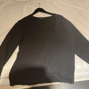 Ralph Lauren Hoodie  - Säljer en klassisk svart tröja från Ralph Lauren, Vädligt bra skick 7,5/10.  Ett litet hål på höger arm, visas i bild 2, passar strl S 