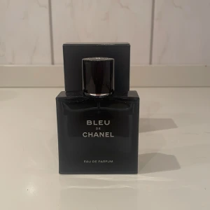 Bleu de Chanel Eau de Parfum - Säljer en elegant och tidlös Bleu de Chanel Eau de Parfum. Flaskan är mörkblå och stilren med en svart kork. Perfekt för den som vill ha en sofistikerad doft med inslag av citrus och tränoter. Kommer med originalförpackning och ett kort från Chanel. Är 50 ml och finns cirka kvar 45 ml i den mängd syns i bild 4. Kan ta vissa byten. Skriv vid funderingar. 😄
