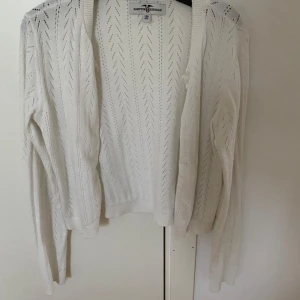 Vit kofta från Hampton Republic - Säljer en stilren vit kofta från Hampton Republic. Koftan har ett diskret hålmönster och långa ärmar. Perfekt på våren och sommaren då den är lite tunnare i materialet. Endast använd en gång och är i nyskick. Säljer pga att den inte kommer till användning. 