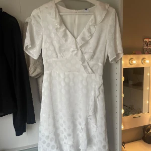 Vit klänning med volangdetaljer - Säljer min jätte fina klänning med volanger då den inte passar längre. Storlek Xs och använd fåtal gånger. Perfekt till midsommar eller skolavslutning!💗