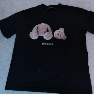 Svart t-shirt från Palm Angels - Snygg svart t-shirt från Palm Angels med ett unikt nalletryck på framsidan och logotypen i gotisk stil på baksidan. Perfekt för en casual look.