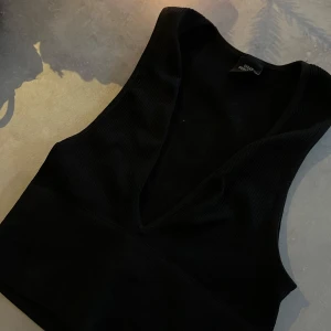 Svart ribbad linnetopp från Urban Outfitters - Snygg svart ribbad linnetopp från Urban Outfitters med djup v-ringning. Endast använd 1 gång