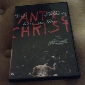 Antichrist DVD - DVD-film av Lars von Trier med Charlotte Gainsbourg. Omslaget är mörkt med röd text och visar en dramatisk scen. Filmen har fått utmärkelser och är känd för sin intensiva handling.