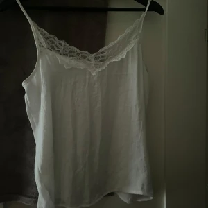 Vit linnetopp  - Säljer en stilren vit linnetopp från Jacqueline de Yong med spetsdetaljer vid halsringningen. Använd fåtal gånger.