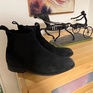 Svarta mocka chelsea boots - Snygga svarta chelsea boots i mocka med klassisk design. Perfekta för både vardag och festliga tillfällen. De har en stilren look och är lätta att matcha med olika outfits.