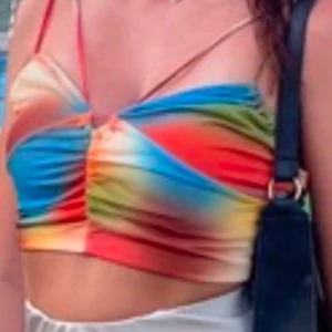 Flerfärgad croppad linnetopp Bershka - Trendig croppad linnetopp i regnbågens färger med smala axelband. Använd ett par tillfällen. Är i storlek M men passar bättre som S