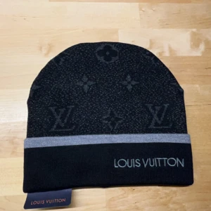 Svart mössa från Loo ouis Vuitto on - Snygg svart mössa från med ikoniskt monogrammönster och grå kant. Perfekt för att hålla stilen i kallare väder. 1 för 700, Pris kan DISKUTERAS