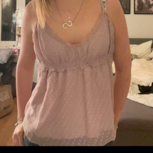 Ljusrosa topp från 3Suisses Collection - Söt ljusrosa topp med spetsdetaljer och v-ringning från 3Suisses Collection. Toppen har ett diskret prickigt mönster och är ärmlös med en lätt volangkant under bysten. Tyvär så står inte storleken men skulle sjävl säga att den sitter som M.