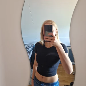 Svarta top med knytning I ryggen - Snygg svart ribbad t-t-shirt med knytning i ryggen. Köparen står för frakten.