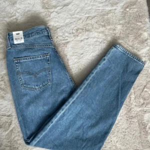 Blå Levi's Premium 80's Mom Jeans - Snygga blå Levi's Premium 80's Mom Jeans med en klassisk högmidjad passform. Perfekta för en avslappnad och trendig stil. Tillverkade i slitstarkt denim med fem fickor och knappgylf. Alldrig använda!