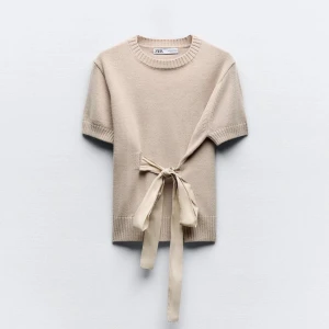 Beige kortärmad tröja från Zara - Säljer en stilren beige tröja från Zara med korta ärmar och knytband i midjan. Tröjan har ribbade kanter vid ärmslut och hals. Perfekt för en avslappnad look. SKRIV TILL MIG INNAN DU KLICKAR PÅ KÖP! ❤️