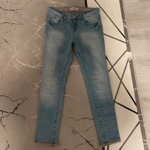 Blå jeans från Zara - Snygga ljusblå jeans från Zara med en klassisk femficksdesign. De har en knappgylf och är tillverkade i denim. Perfekta för en avslappnad stil.