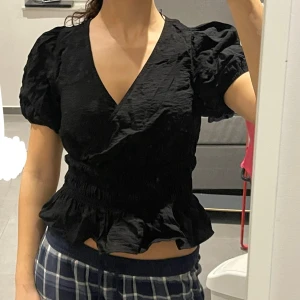 Svart blus med volangdetaljer från Vero Moda.  - Snygg svart blus med korta puffärmar och volangdetaljer i nederkant. Skriv privat för mer bilder eller andra frågor :) 