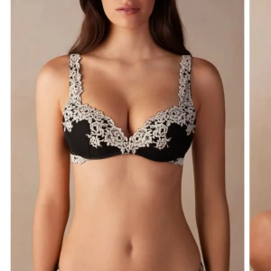 Svart bh med spetsdetaljer - Elegant svart bh med vackra spetsdetaljer i vitt. Den har breda axelband och en djup urringning som ger en fin form. Perfekt för att känna sig extra fin under kläderna.