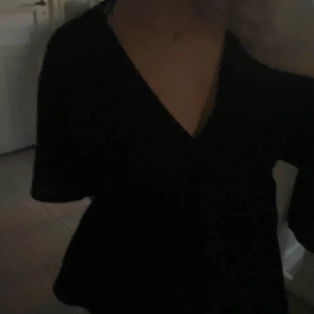 Säljer en stilren svart blus från Lindex i storlek M. Blusen har en v-ringad design och korta ärmar, perfekt för en elegant look. Den är tillverkad i ett mjukt och bekvämt material.. Yläosat.