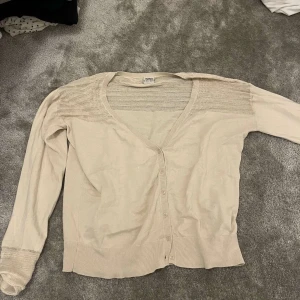 Beige kofta från Esprit - Säljer en stilren beige kofta från Esprit med knappar framtill. Koftan har ett stickat mönster på axlarna och ryggen. Koftan är en L men sitter som en M