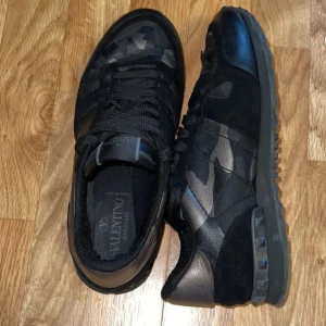 Valentino Rockrunner i svart och kamouflage - Snygga Valentino Rockrunner sneakers i svart. Skorna är använda och har en del defekter men inget som direkt syns när du har på dig skorna. Dom är fortfarande super bekväma och stilrena. Lite defekter i hälen och längs fram på skon. Inget OG följer med tyvärr men självklart äkta! Pågrund av defekterna så kommer självklart priset gå ner så jag säljer dessa endast för 1399kr vilket är ett helt sjukt bra pris!