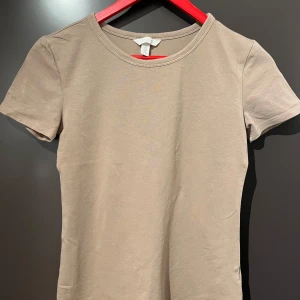 Brun t-shirt från HM - ALDRIG ANVÄND men nytvättad. behöver bara bli av med. Helt ny, inga defekter såklart. Sitter tight