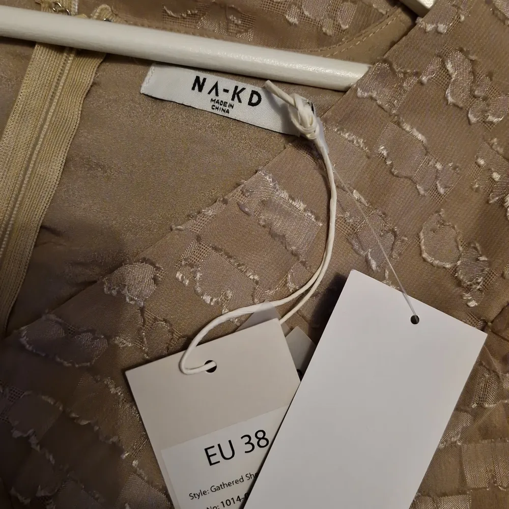 Säljer en helt oanvänd beige klänning från NA-KD med ett unikt mönster och voluminösa trekvartsärmar. Klänningen har en v-ringad design och rynkade detaljer som ger en smickrande passform. Perfekt för speciella tillfällen! Obs liten i storlek. Mekot.