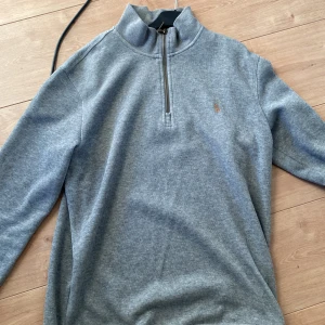Ralph lauren half zip - Säljer en stilren grå tröja från Ralph Lauren med halv dragkedja framtill. Tröjan har en diskret logga på bröstet och är perfekt för en avslappnad look. Storleken är M. Hör av dig vid frågor och funderingar. 
