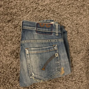 Dondup jeans - Snygga blå jeans från Dondup i den trendiga modellen ”George skinny fit” De har en klassisk femficksdesign och slitna detaljer på framsidan för en trendig look. Perfekta för en avslappnad stil. Tveka inte på att höra av dig vid eventuella frågor eller funderingar.