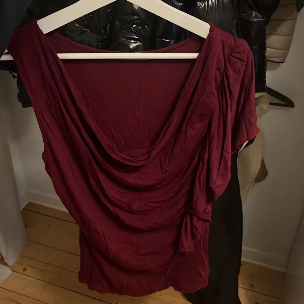Säljer en vinröd topp från Soaked in Luxury. Toppen har en draperad design med en kortare ärm och en lös passform. . Yläosat.