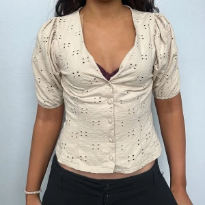 Beige blus från H&M - Säljer en söt beige blus från H&M med korta puffärmar och knappar framtill. 