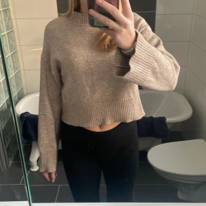 Beige stickad tröja - Beige/brun stickad tröja. Lite kortare i magen och längre i ärmarna,även lite högre i halsen. Mudd i nedrekant,ärmarna och halsen. Den är från barnavdelningen och stl 170.
