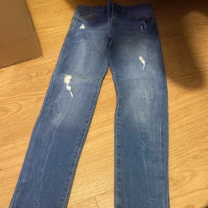 Blå jeans från LC Waikiki - Snygga blå jeans från LC Waikiki med slitna detaljer. Den stängs med knapp och dragkedja. Perfekta för en avslappnad stil. Helt nya med prislapp. 