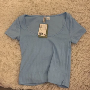 Ljusblå kortärmad topp från Bershka - Säljer en ljusblå topp med korta ärmar och rund halsringning. Perfekt för en avslappnad stil. Toppen är i ett mjukt och bekvämt material.