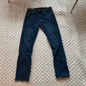 Levi's 501 jeans - Klassiska Levi's 501 jeans i en snygg mörkblå färg. De har en rak passform och är tillverkade i slitstarkt denim. Perfekta för en avslappnad stil med fem fickor och knappgylf. Använd fåtal gånger. Väldigt sköna.