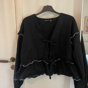 Svart volang blus  - Super fin blus köpt på Nelly från Pieces. Fina volang detaljer med vit kant samt snörning.