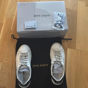 Vita palm  Angels sneakers - Snygga vita sneakers från Palm Angels med svart häl. Skorna har vita snören och svartvita som kommer med. Levereras med originalförpackning och extra skosnören.