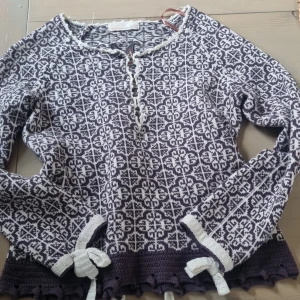 Odd Molly kofta/ tröja - Säljer en snygg mönstrad stickad tröja från Odd Molly i svart och vit. Tröjan har långa ärmar och dekorativa knytband både i slutet av ärmarna och bak på ryggen.