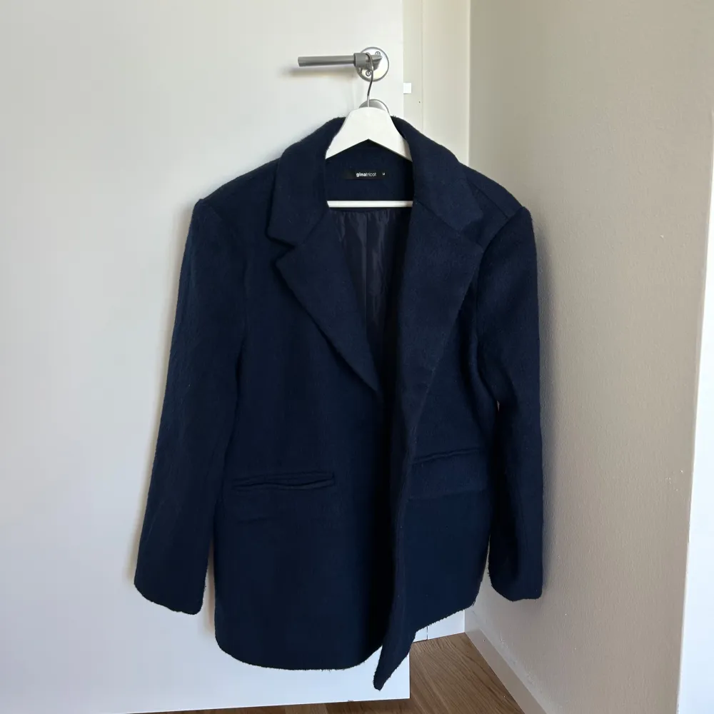 Slutsåld mörkblå kavaj från Gina Tricot. Strl M. Använd 1-2 ggr, som ny!💖 Beskrivning från hemsidan: Oversized jacket in men's style with wide sleeves. The jacket is blue and has a brushed quality in wool mix. It has one-button fastening at the front, dropped shoulders, collar with notch lapel, welt pockets with flaps in the sides and a chest pocket.. Takit.