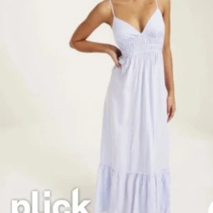 Blåvit randig långklänning - Säljer en somrig blåvit randig långklänning med smala axelband och v-ringning. Klänningen har en luftig passform och är perfekt för varma dagar. Den har en volangdetalj längst ner som ger en extra touch. Perfekt för en avslappnad stil.