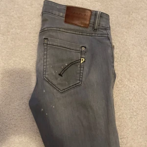 Dondup jeans  - Snygga grå jeansbyxor med slitningar för en trendig look. De har en klassisk femficksdesign och en knappgylf. Perfekta för en avslappnad stil.