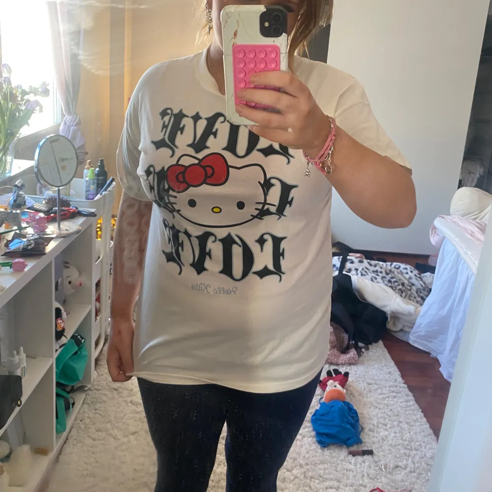 Säljer en vit t-shirt med Hello Kitty-tryck och texten 'LOVE' i gotisk stil. T-shirten har korta ärmar och är gjord av bomull. Perfekt för alla Hello Kitty-fans! 🐱❤️. T-paidat.