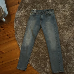 Levi’s jeans blåa - Snygga blå jeans från Levi's med klassisk femficksdesign och dragkedja. Perfekta för en avslappnad stil. De har en straight passform och är tillverkade i slitstarkt denim. Sitter tajt i passformen. 