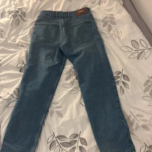 Blå jeans från Axel Arigato - Snygga blå jeans från Axel Arigato med klassisk femficksdesign och en bekväm passform. De har en dragkedja och knapp framtill samt en stilren läderpatch med logotyp baktill. Perfekta för en avslappnad stil.