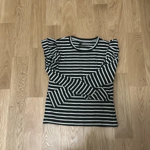 Randig tröja från Zara - Säljer en randig tröja från Zara i svart och vit. Tröjan har långa ärmar och volangdetaljer vid axlarna. Perfekt för en stilren look. Hör av dig vid intresse!🩷🩷