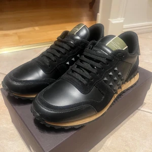 Valentino Rockstud sneakers – svart, storlek 43 – nära nyskick! - Säljer ett par exklusiva Valentino Rockstud sneakers i svart, storlek 43. Skorna är i nästan nyskick, använda vid ett tillfälle och kommer med originalkartong.  Modellen kännetecknas av Valentinos ikoniska premiumläder och en bekväm design som kombinerar lyx och streetwear på bästa sätt. Perfekta för dig som vill ha stilrena och exklusiva sneakers som sticker ut!  Nypris ca 6 150 kr – mitt pris: 3 199 kr.