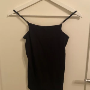 Svart linnetopp från H&M - Säljer en stilren svart linnetopp från H&M och ett vitt basic linne. Toppen har smala axelband och en enkel design som passar perfekt till olika tillfällen. Perfekt för varma dagar eller som ett basplagg i garderoben. 19kr styck!