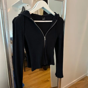 Mörkblå ribbad tröja från Gina Tricot - Snygg mörkblå ribbad tröja med  luva från Gina Tricot med dragkedja framtill. Den har en åtsittande passform och långa ärmar. Perfekt för en casual look.